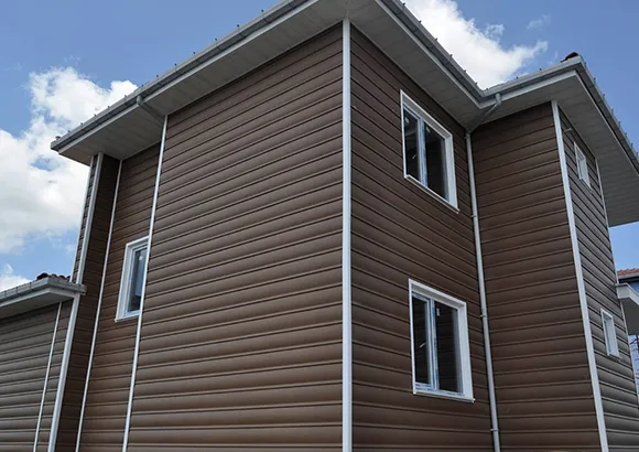 Dark brown vinyl siding on a multi-story home in South Easton, MA with white-trimmed windows and blue sky.