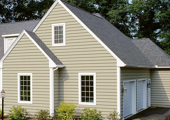 Beige vinyl siding on a traditional single-family house in Stoughton, MA with white window frames and green lawn.