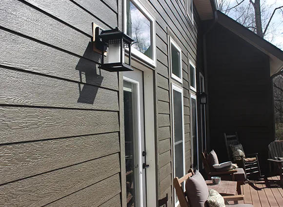Close-up of modern beige vinyl siding on a residential home with outdoor patio light fixture.